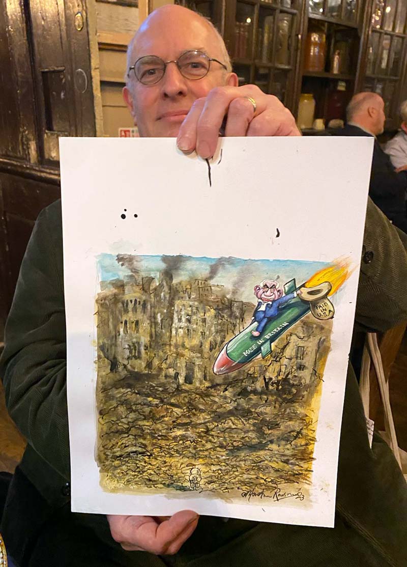 A photo of Martin Rowson holding up one of his cartoons