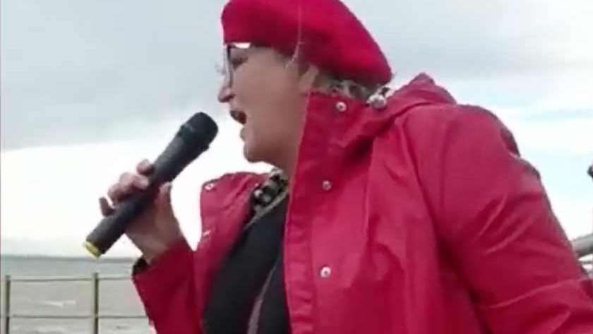 A picture of Karen Constantine wearing a red coat and holding a microphone