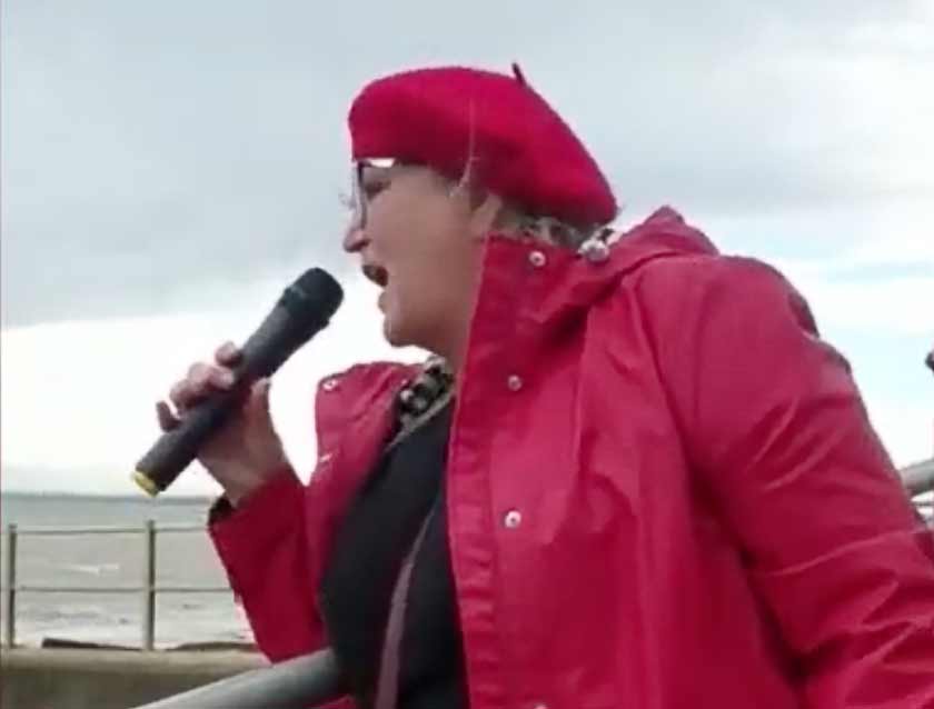 A picture of Karen Constantine wearing a red coat and holding a microphone