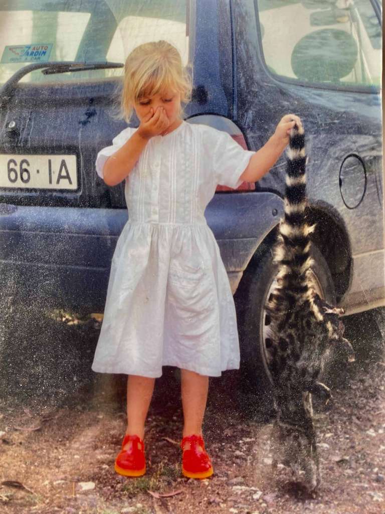 Young girl holding her nose whilst holding 'roadkill' by the tail.